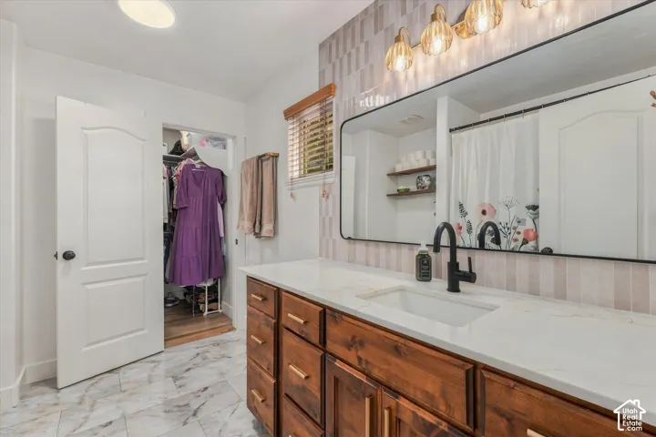 Wood-finish vanity with gold-tone hardware, white countertop, rectangular undermount sink, and matte black faucet