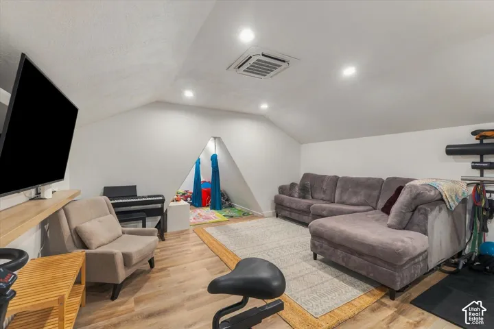 Sloped ceiling room featuring recessed lighting, wood-finish flooring, and a built-in wall niche