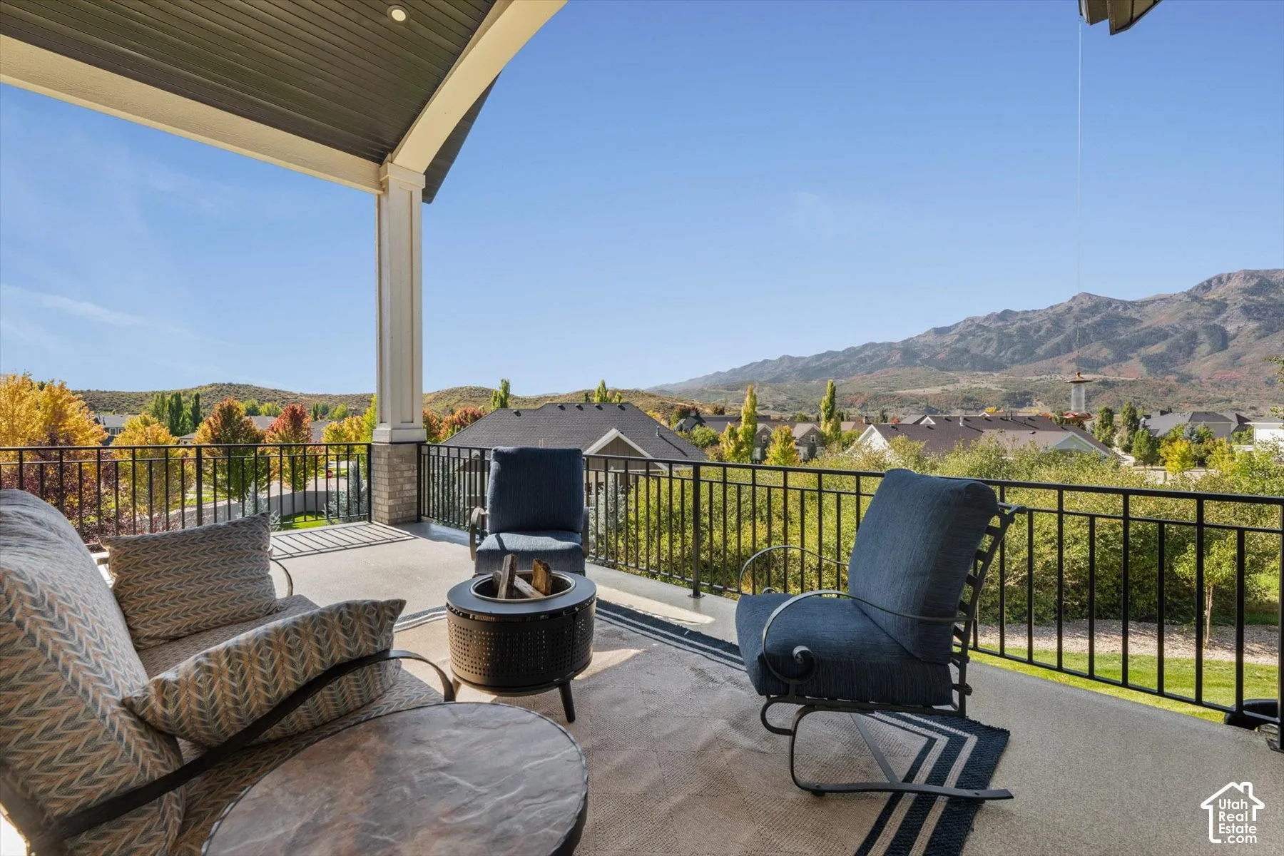 Covered outdoor patio with a concrete surface, black metal railing, and recessed lighting