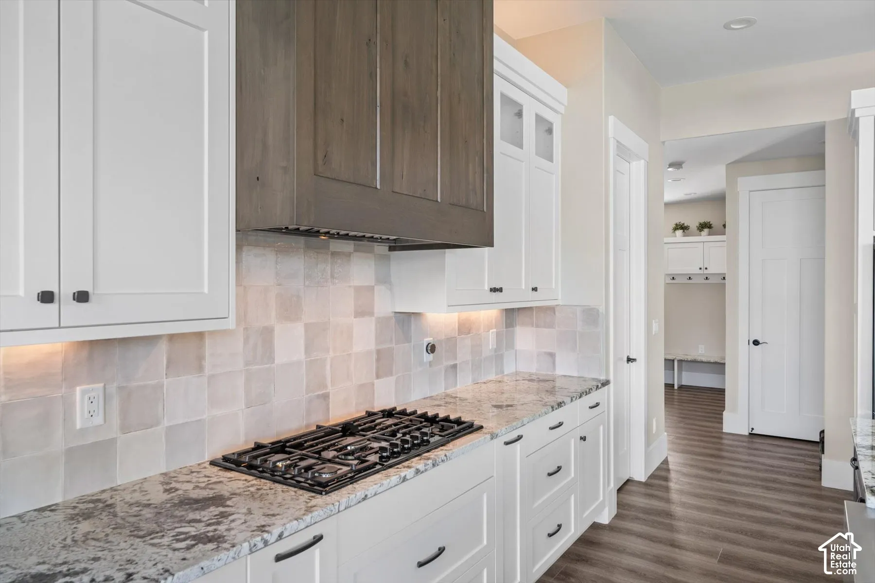 Kitchen with white shaker cabinetry, speckled countertops, square tile backsplash, and a gas cooktop