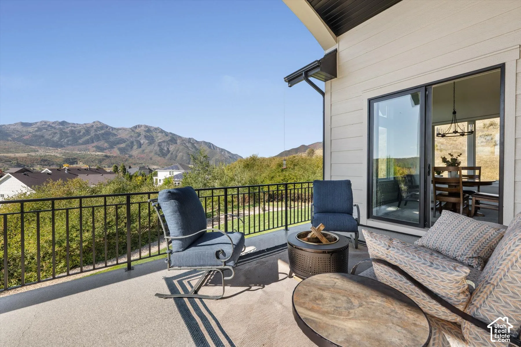 Expansive outdoor deck with mountain scenery, black metal railing, and a large sliding glass door
