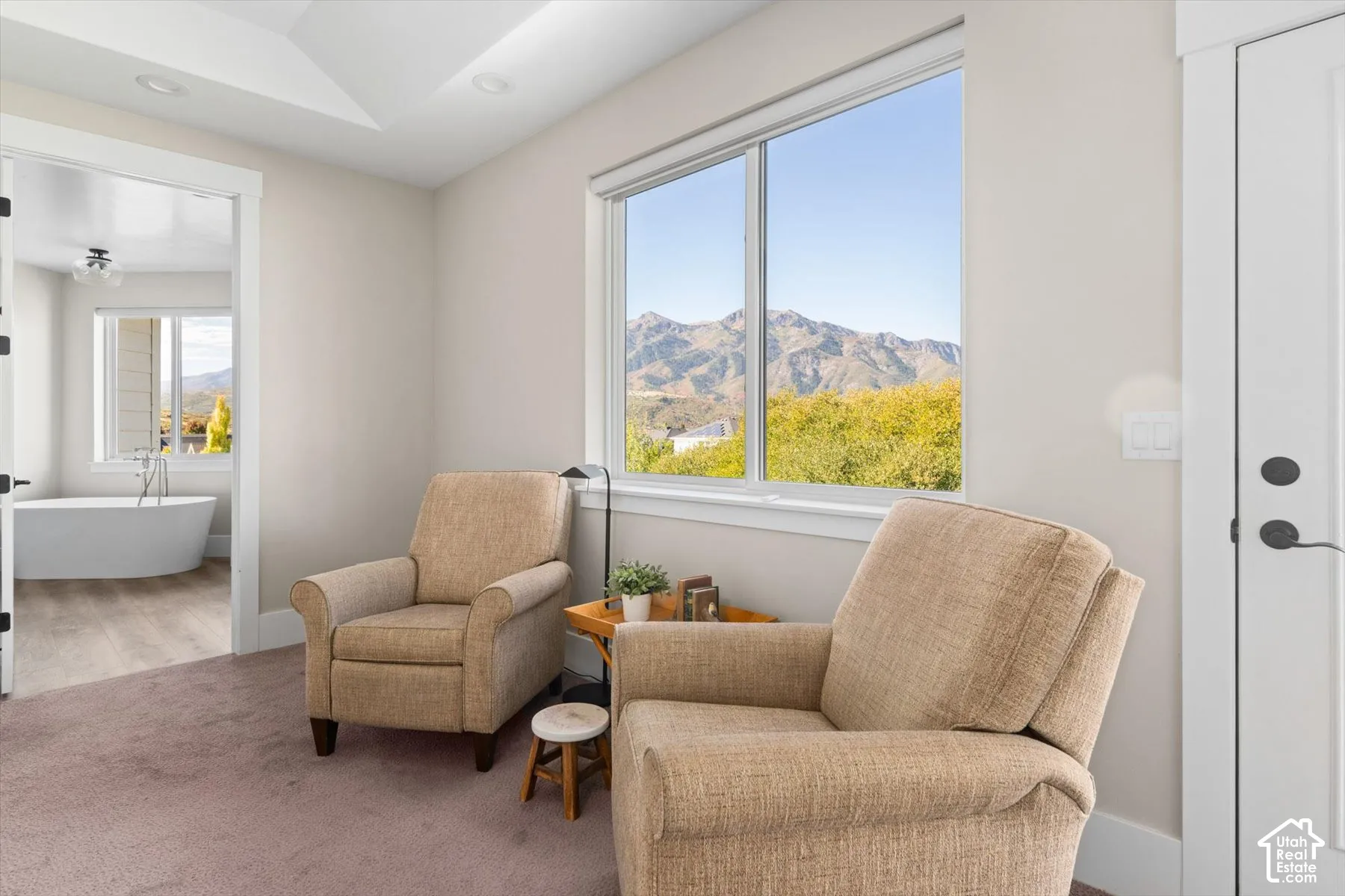 Large window with mountain backdrop, recessed lighting, tray ceiling, and an adjoining space with a freestanding soaking tub
