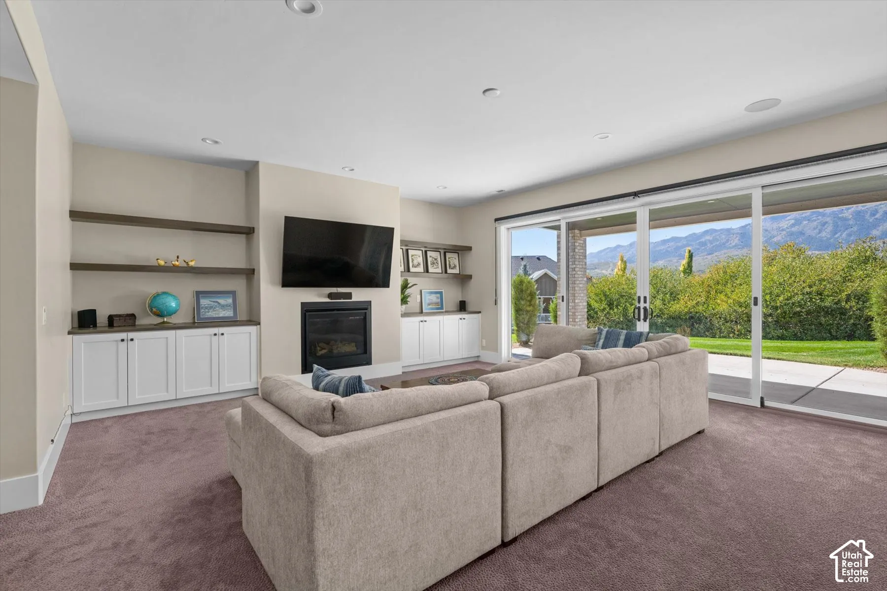 Recessed lighting, built-in shelving, and a modern fireplace with a dark surround