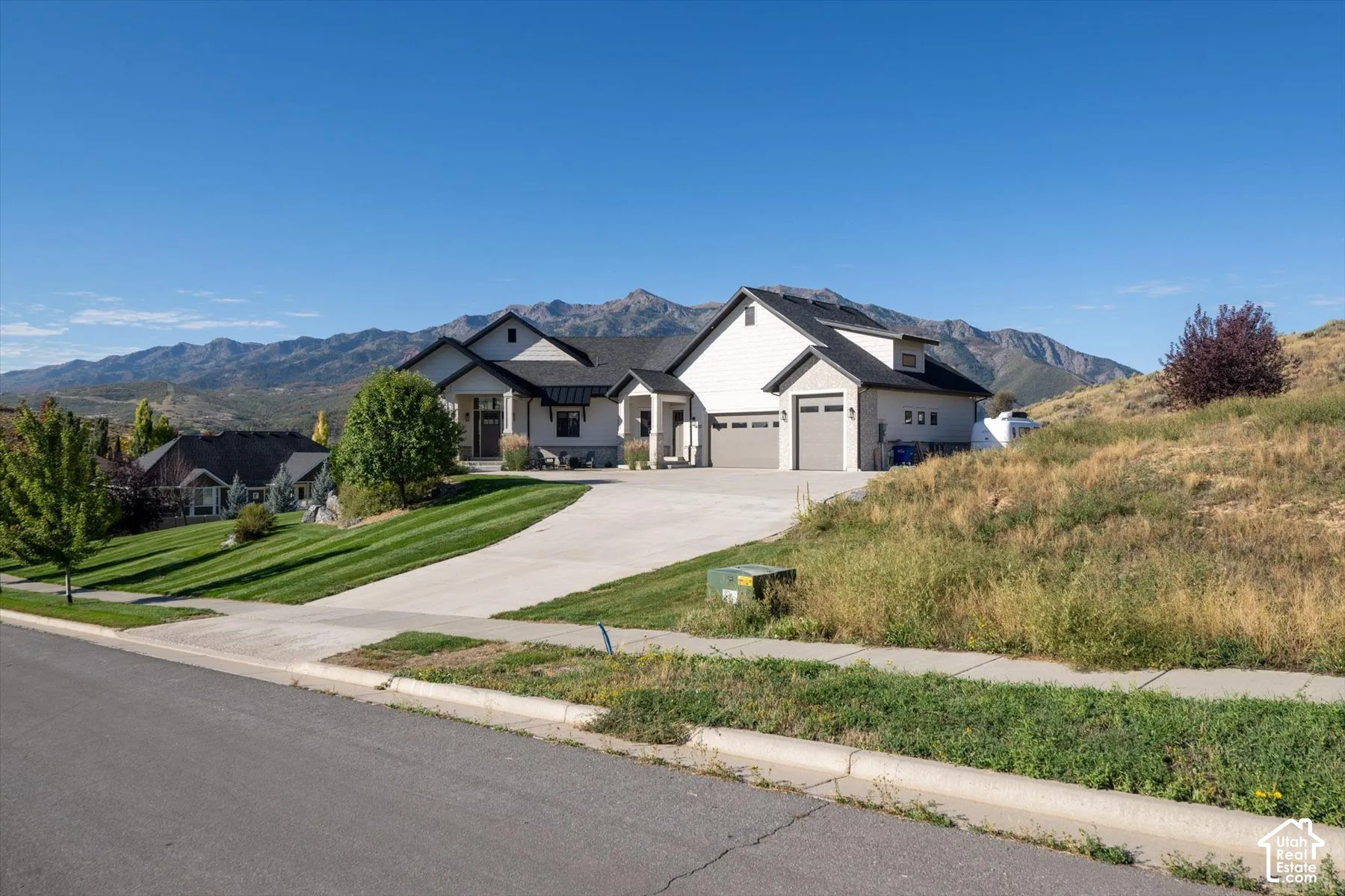Contemporary-style exterior with a light-toned stucco finish, dark-toned roof, and an attached two-car garage