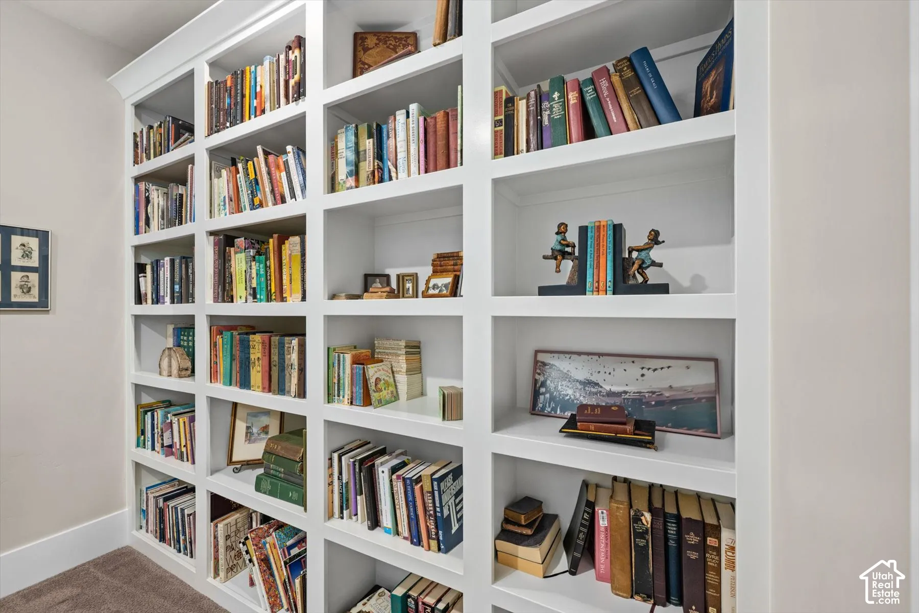 Built-in white shelving with extensive storage, crown molding, and carpeted flooring
