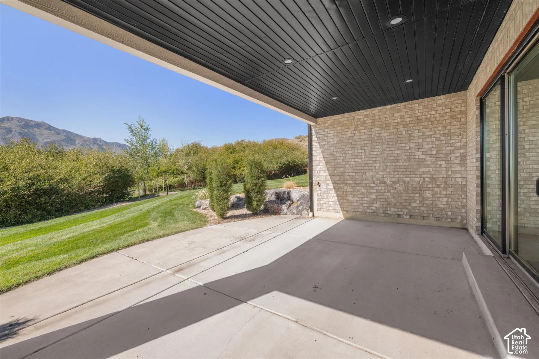 Expansive concrete patio with a dark panel ceiling and recessed lighting
