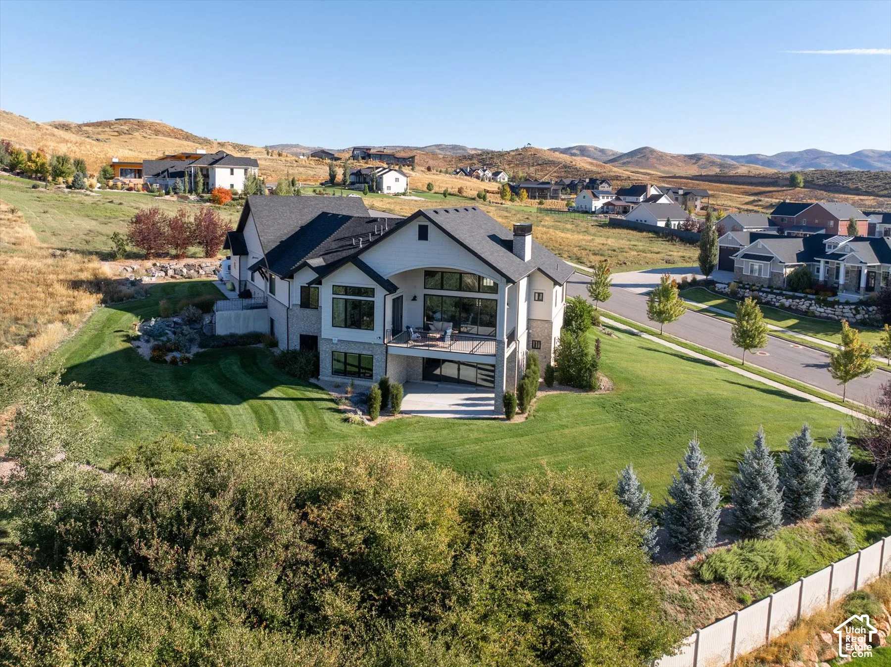 Modern architectural design with a multi-level deck, expansive lawn, and surrounding natural landscape