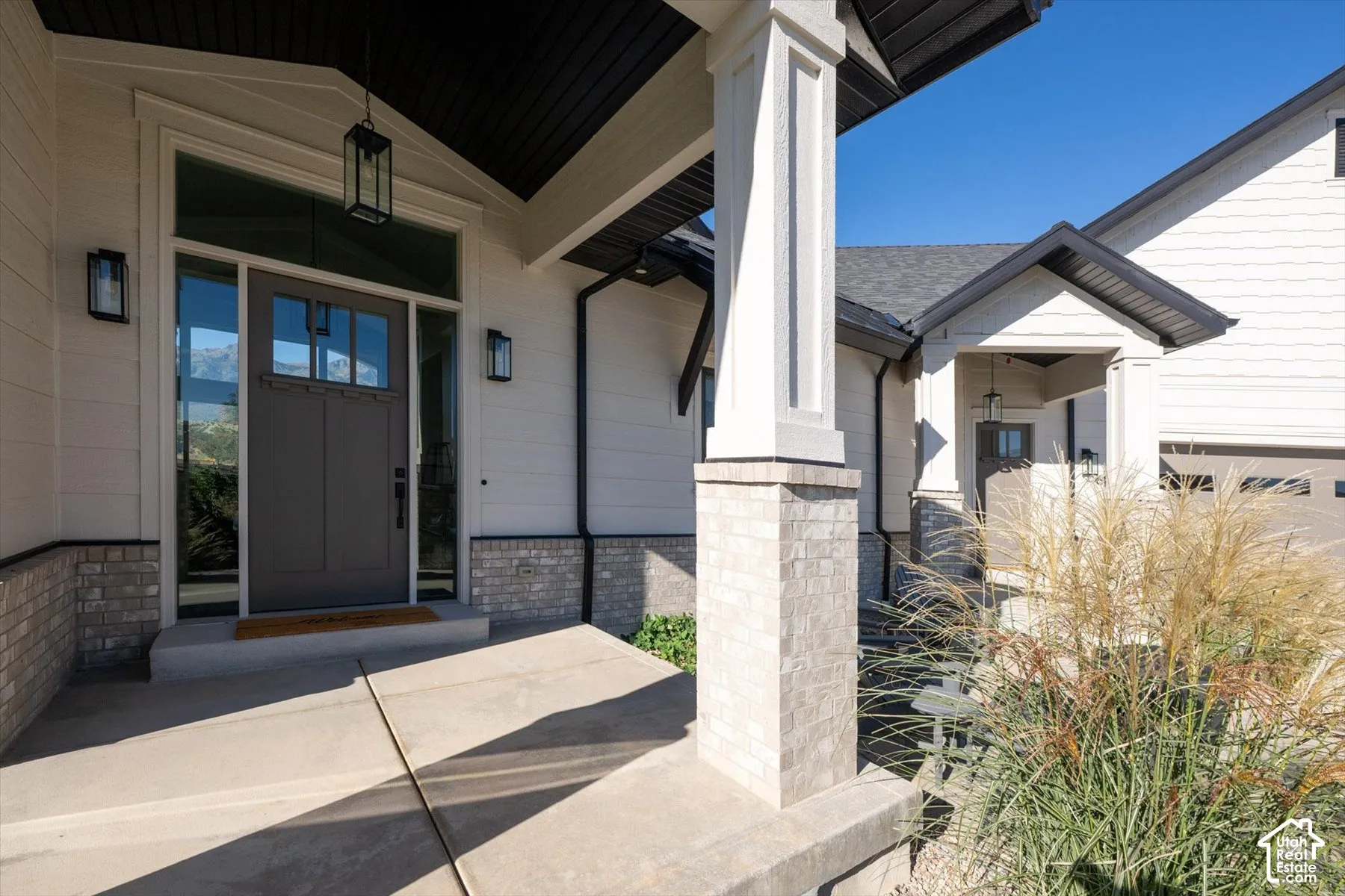 Covered entryway featuring a dark gray door with glass panels, sidelights, and overhead transom window