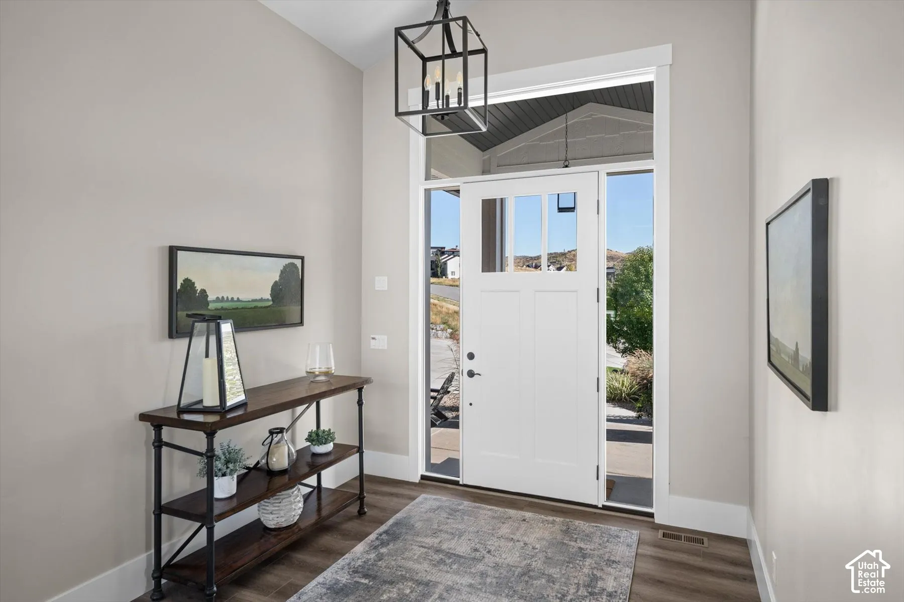 Transom windows above a white entry door, framed by sidelight windows and wood-finish flooring