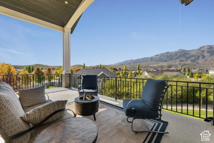 Covered outdoor patio with a concrete surface, black metal railing, and recessed lighting