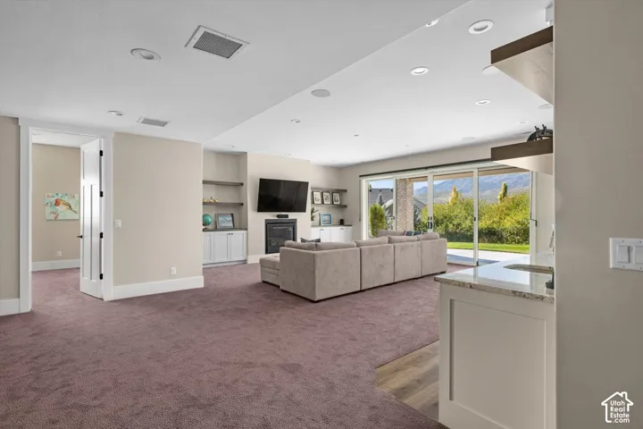 Recessed lighting throughout, built-in shelving, fireplace, and sliding glass doors to outdoor patio
