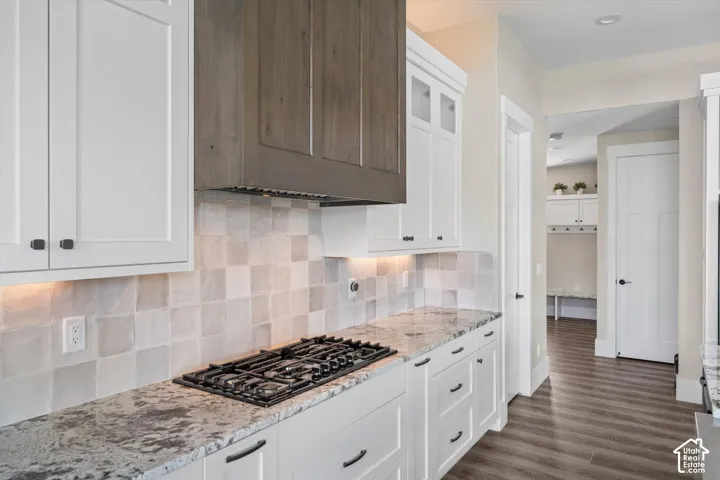 Kitchen with white shaker cabinetry, speckled countertops, square tile backsplash, and a gas cooktop