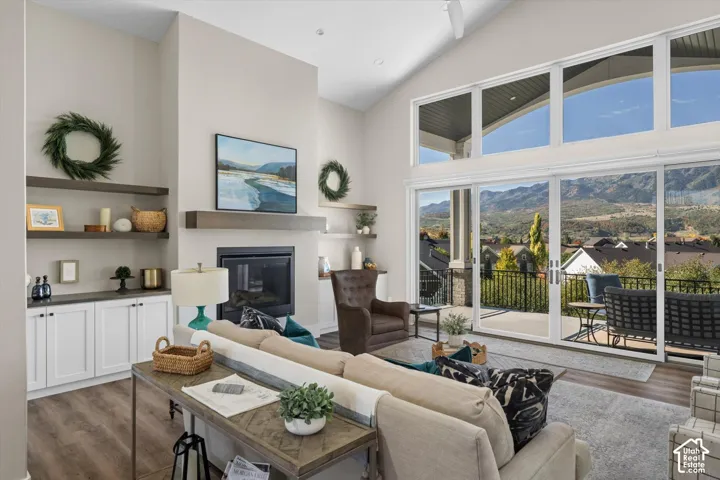 Vaulted ceilings with a ceiling fan, a built-in fireplace with a mantel, built-in shelving and cabinetry, wood-finish flooring, and large sliding glass doors leading to an outdoor patio