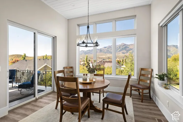 Expansive windows, wood-finish flooring, a contemporary chandelier, and a sliding glass door to an outdoor balcony