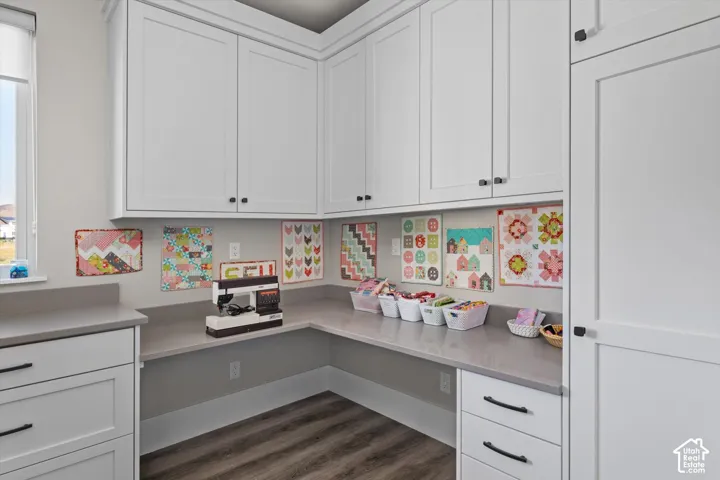 Extensive white cabinetry with dark hardware, expansive countertop space, and wood-finish flooring