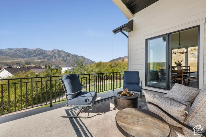 Expansive outdoor deck with mountain scenery, black metal railing, and a large sliding glass door