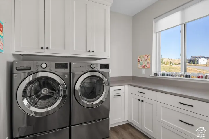White shaker-style cabinetry with matte black hardware, stone-finish countertops, and wood-finish flooring