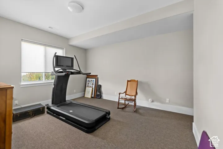 Recessed ceiling light, neutral wall color, window with roller shade, carpeted flooring, and white trim