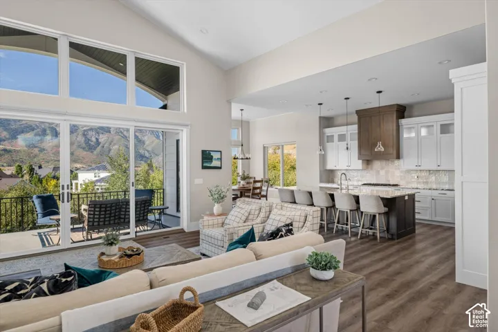 Vaulted ceilings with clerestory windows, expansive sliding glass doors, a large balcony, a central kitchen island with seating, and wood-finish flooring throughout