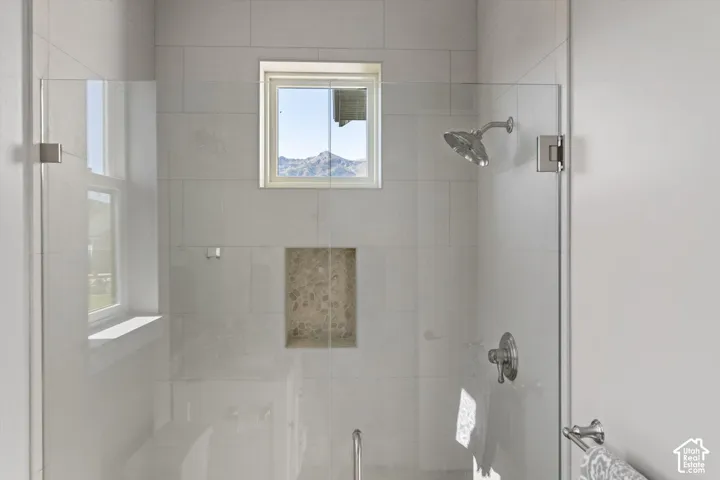 Glass-enclosed shower featuring large format tile, a built-in stone niche, and a window for natural illumination