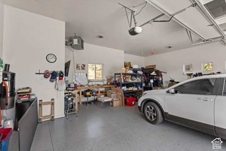 Two-car garage featuring finished walls, an automatic garage door opener, and multiple windows