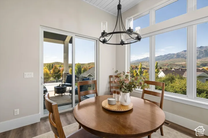 Vaulted ceiling with shiplap detail, large picture windows, sliding glass door access to an outdoor patio, and a modern chandelier