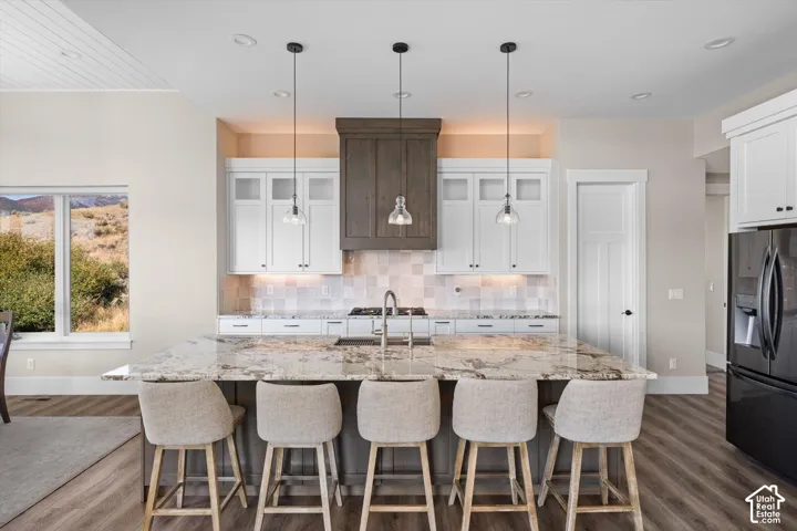 Central kitchen island with a stone countertop, equipped with a sink and pendant lighting