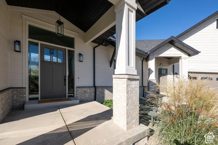 Covered entryway featuring a dark gray door with glass panels, sidelights, and overhead transom window