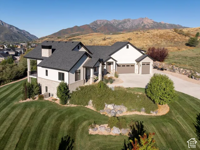 Elegant two-story residence featuring a modern architectural design with mixed exterior finishes, a three-car garage, and manicured landscaping with mature evergreen plantings and decorative rock borders
