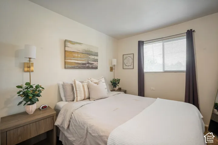 Wall-mounted sconce lighting, window with blinds, and wood-finish flooring