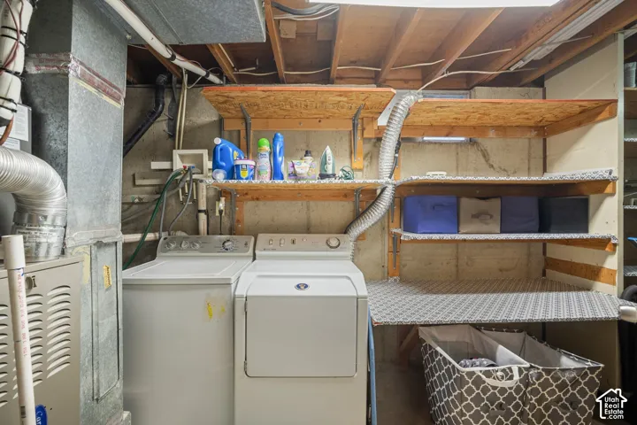 Laundry area featuring a washer and dryer, built-in shelving, exposed ceiling joists, and a utility sink connection