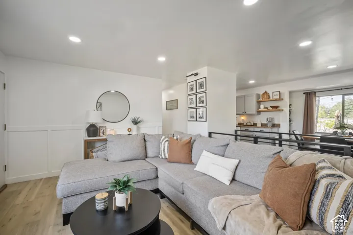 Recessed ceiling lighting, wood-finish flooring, half-wall with metal railing, panel accent wall, and built-in shelving