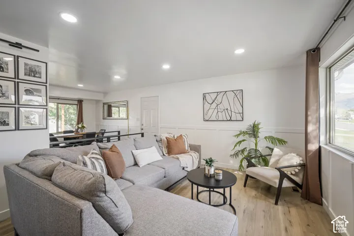 Recessed lighting illuminates the living space featuring wood-finish flooring and wainscoting