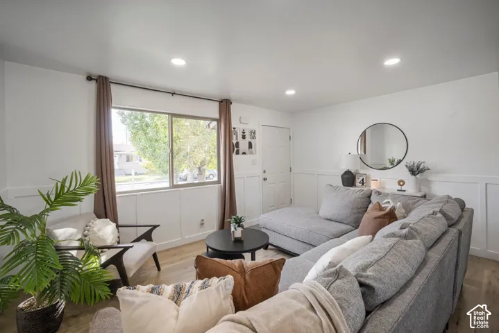 Recessed lighting, wood-finish flooring, white paneled wall trim, white interior door, and a large window