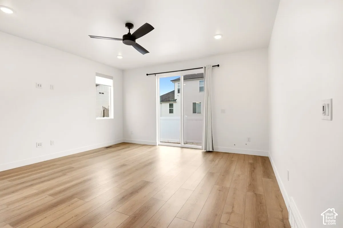 Wood-finish flooring, recessed lighting, matte black ceiling fan, and glass sliding door featuring exterior access