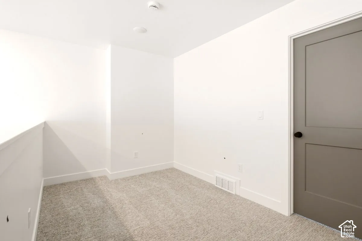 Neutral wall tones, wall-to-wall carpeting, and a shaker-style interior door with matte black hardware
