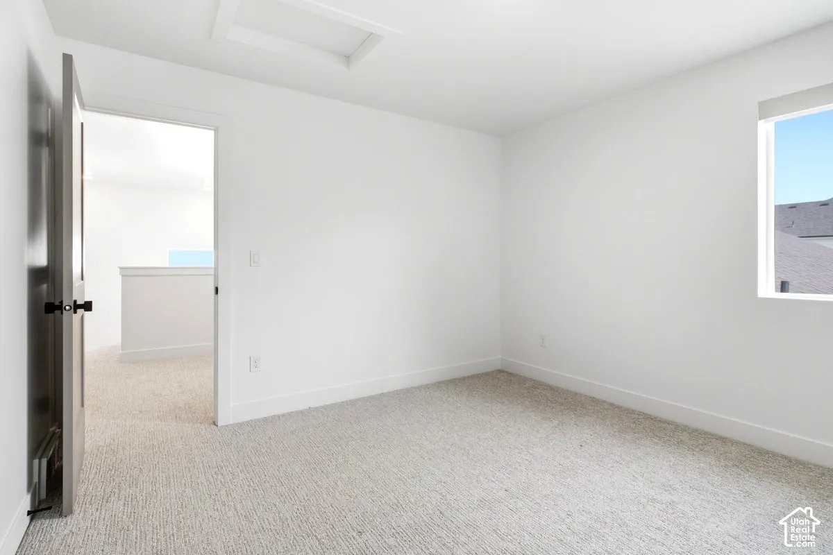 Light-toned carpeting with white walls, a single window, and a dark paneled door