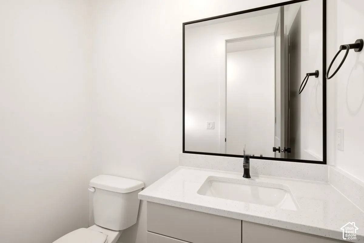 Bathroom featuring a vanity with a white countertop and rectangular undermount sink, a large mirror with a matte black frame, and matte black fixtures