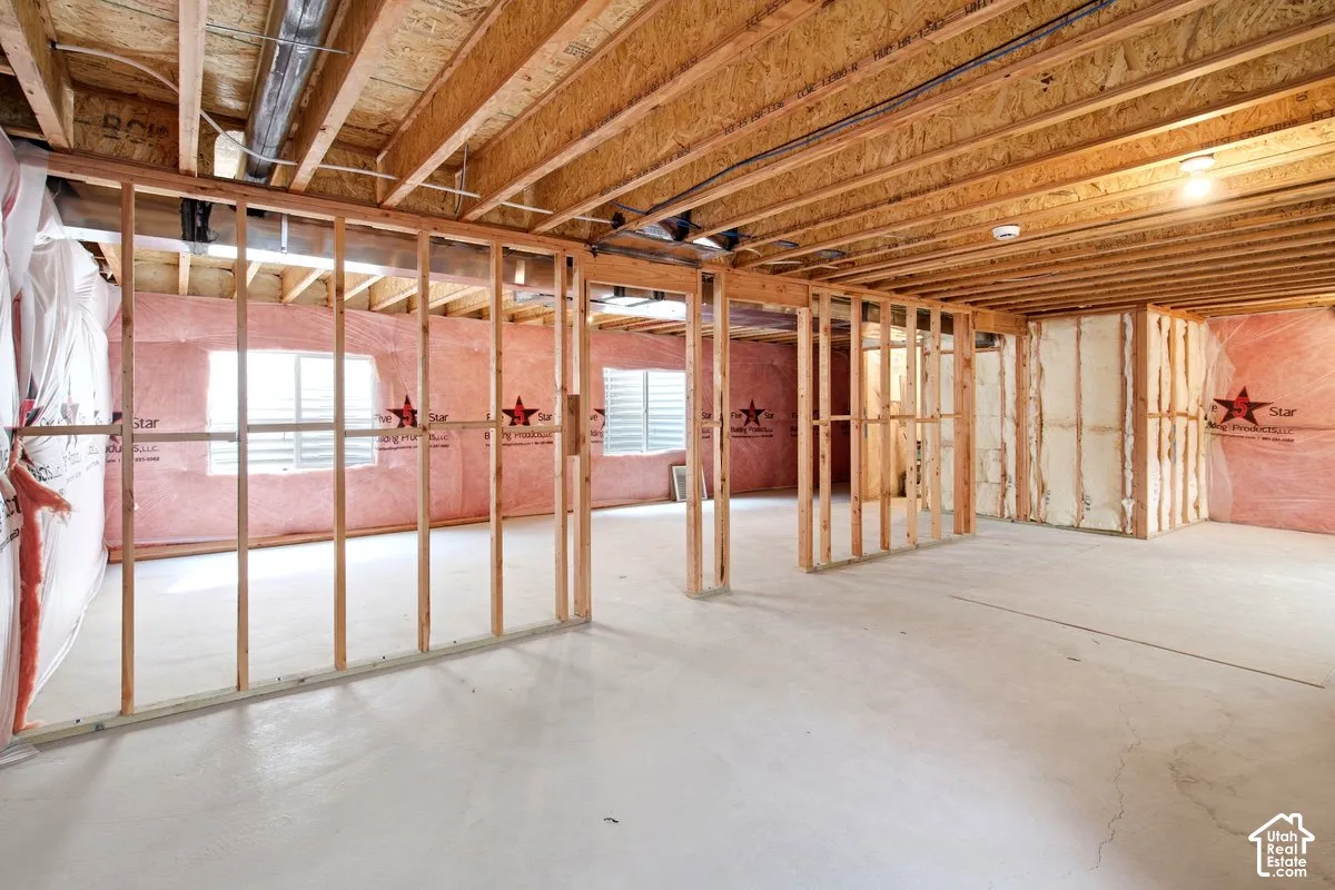 Unfinished basement with framed walls, exposed ceiling joists, insulation, and concrete flooring