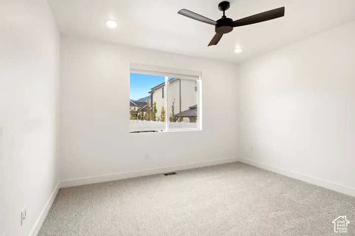 Neutral-toned carpeted flooring, matte black ceiling fan, and recessed overhead lighting