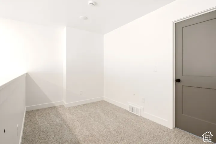 Neutral wall tones, wall-to-wall carpeting, and a shaker-style interior door with matte black hardware