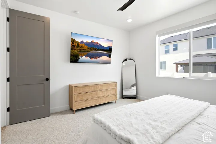 Recessed ceiling lighting, a ceiling fan, a framed window, and light-toned carpeting