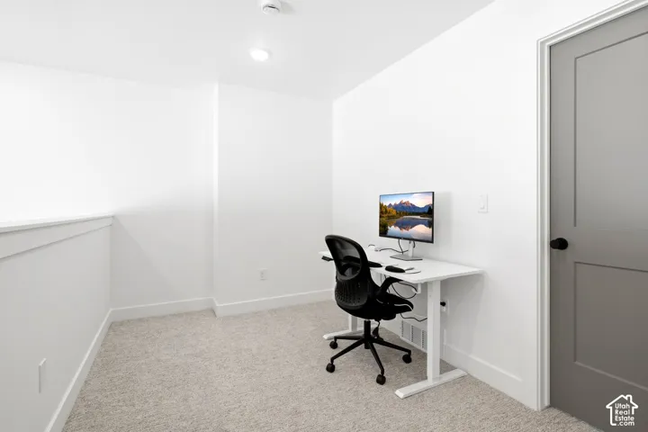 Recessed lighting, light-toned carpeting, crisp white walls, and a contemporary gray paneled door with a black knob