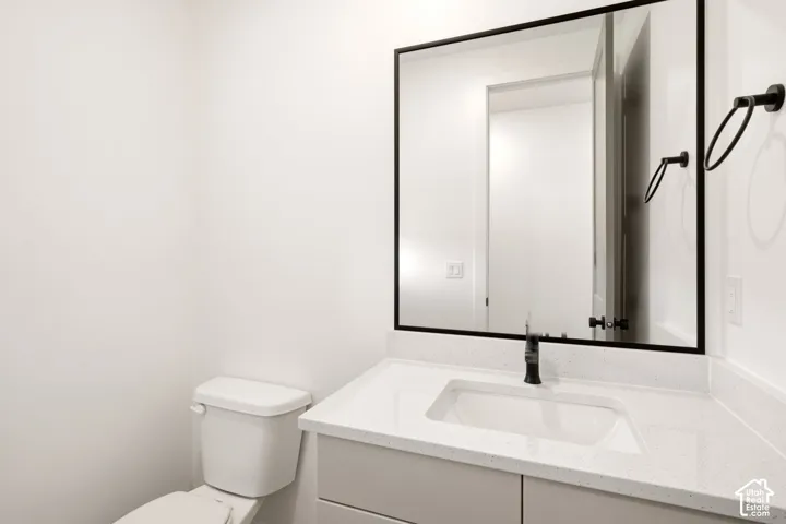 Bathroom featuring a vanity with a white countertop and rectangular undermount sink, a large mirror with a matte black frame, and matte black fixtures