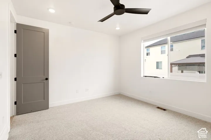 Neutral-toned carpeting, matte black ceiling fan, solid-core grey interior door, and recessed lighting