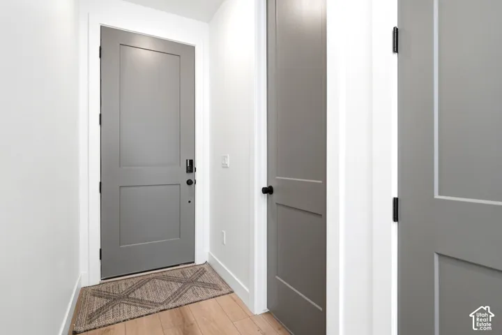Light wood-finish flooring with white baseboards and painted interior doors