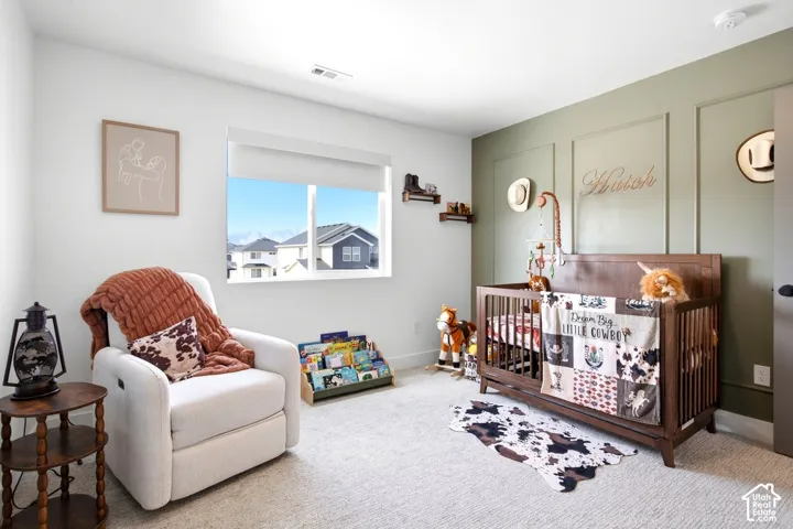Accent wall with panel molding, large window, light-colored carpet flooring, recessed ceiling light, and a dark-toned door