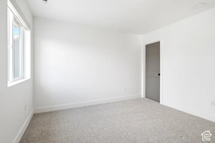 Bright room featuring light-colored carpeting, white painted walls, and a single window