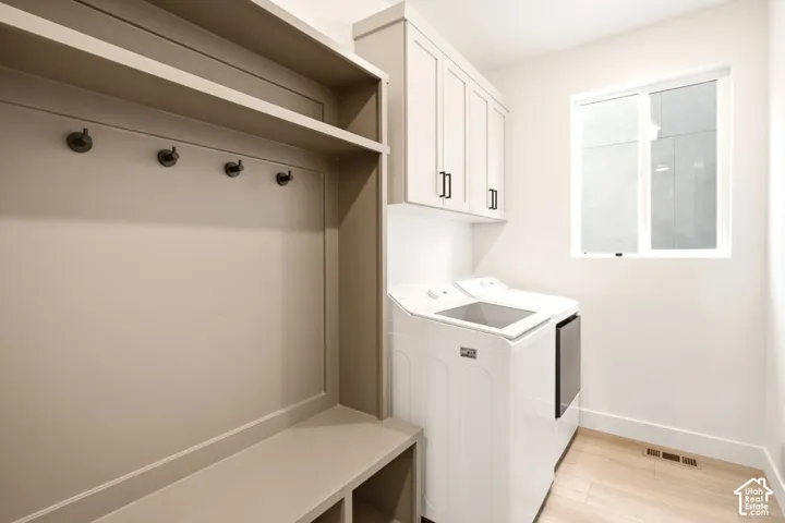 Built-in bench with upper storage shelving, wall-mounted coat hooks, neutral-finish cabinetry, and wood-finish flooring