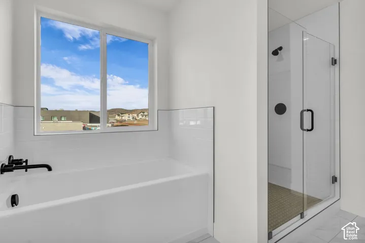 Built-in bathtub with matte black fixtures, white subway tile surround, and Euro glass shower enclosure featuring matte black hardware and a patterned shower floor.